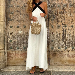 woman wearing a long white sleeveless summer dress with a wicker bag in her hand 